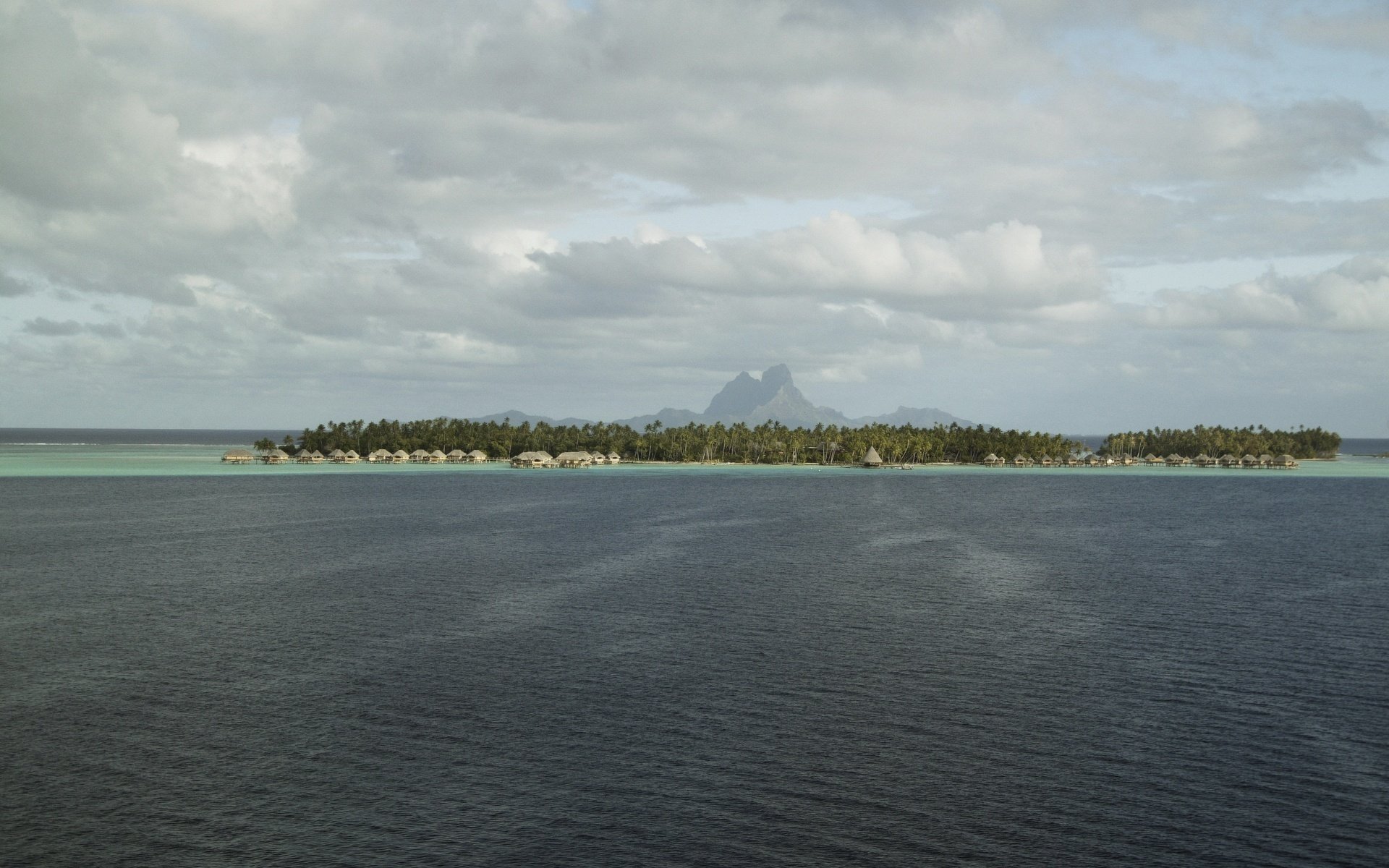 île dans la mer vague bleue verdure eau ciel ciel gris ondulations nuages nuageux île océan tropiques montagnes végétation arbres maisons sur l eau