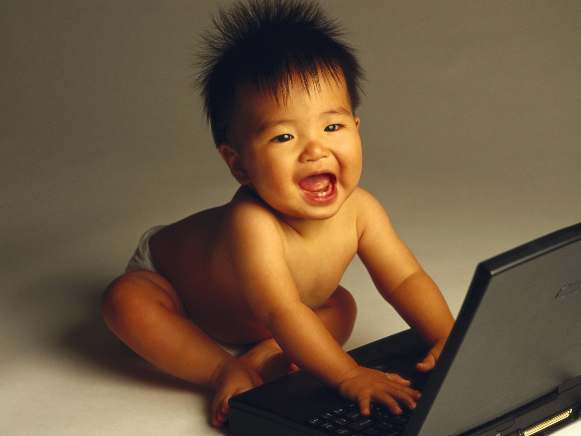 primeros dientes bebé admiración mirada sonrisa computadoras portátil asiático miga juegos bromas intranquilidad juguete deleite ojos cara