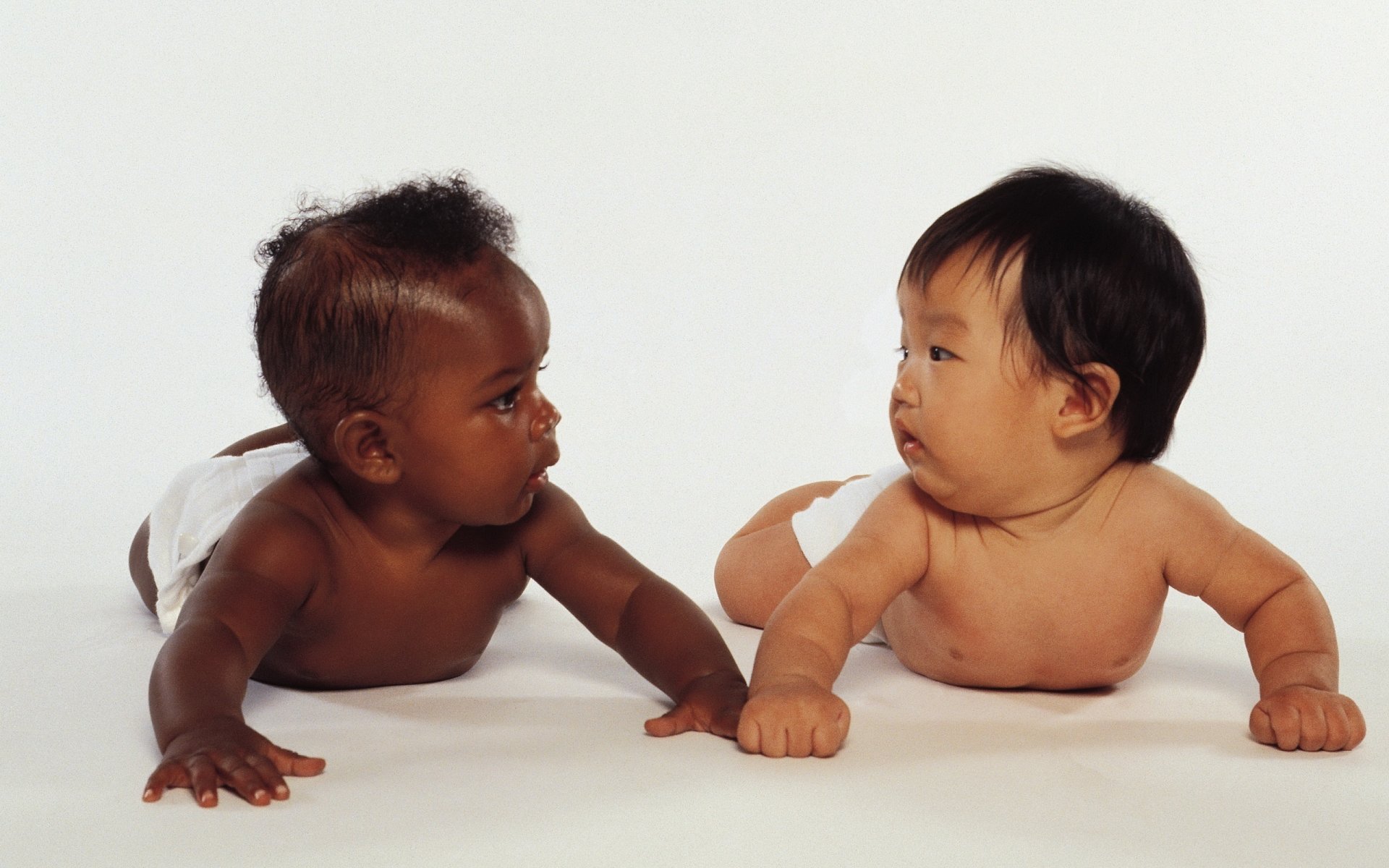 telepatía comunicación a través de los ojos bebés amistad negra asiática dos niños migajas diferentes razas fondo blanco cara mirada