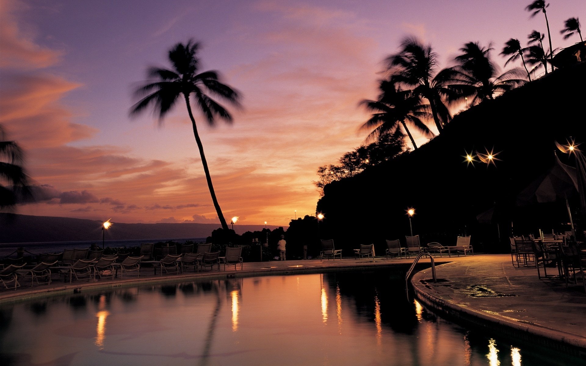 wasseroberfläche abend taschenlampen sonnenliegen pool sonnenuntergang palmen himmel erholung hotel resort liegestühle silhouetten halbdunkel bäume tropen rosa himmel lichter reflexion