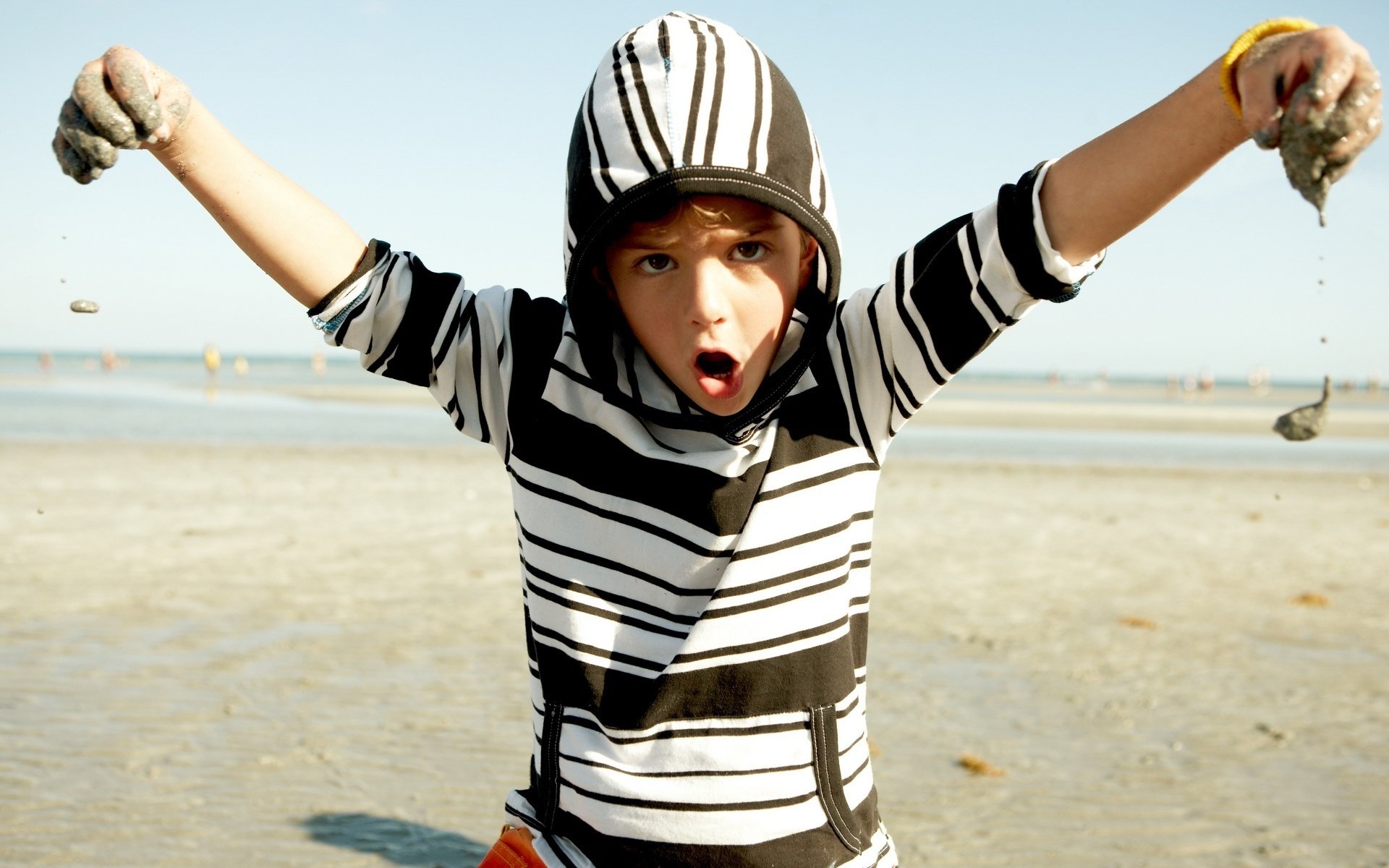fooling around wet sand in the hands boy creek eyes face hood nature dirt hands fun game prank