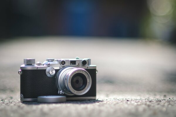 A camera with an open lens on the ground