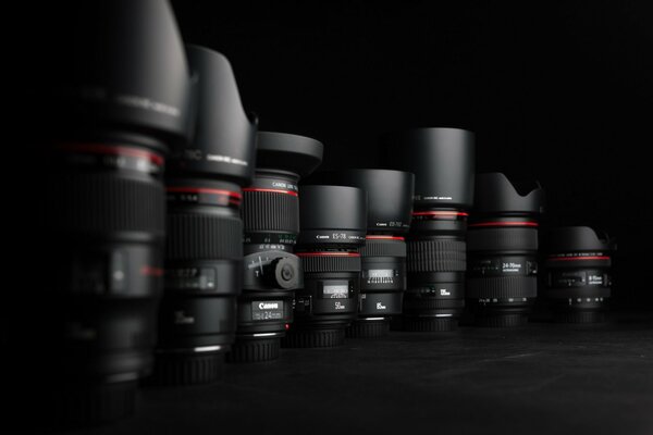 A line of different canon lenses with lens hoods