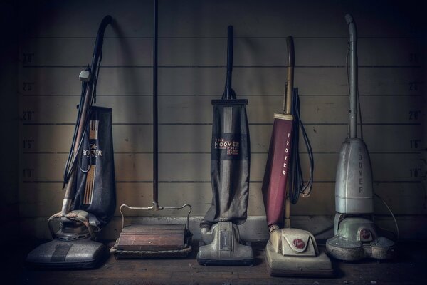 Collection of vintage vacuum cleaners on the wall background