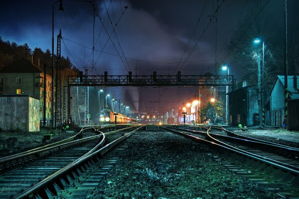 Ferrocarril por la noche entre pequeñas casas