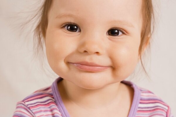 Brown-eyed smiling little girl in a striped T-shirt