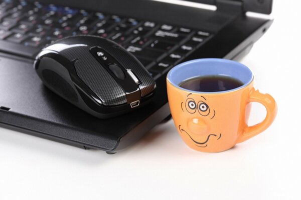Portátil con ratón y taza triste