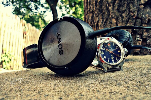 El reloj y los auriculares yacen en el Suelo cerca de un árbol