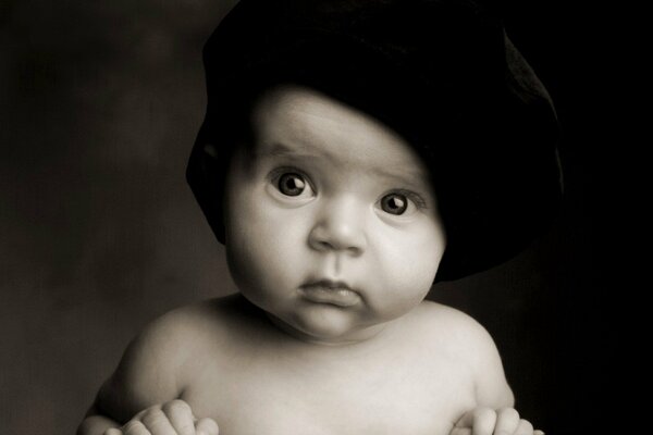Il bambino con il cappello nero guarda sorpreso