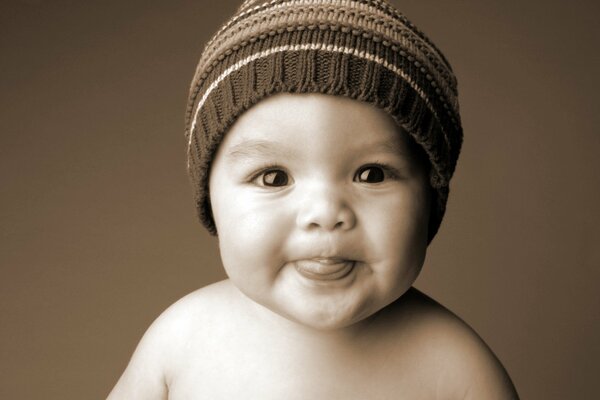 Un bambino piccolo in un cappello mostra la lingua