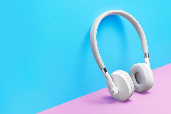 White wireless headphones on pink and blue background
