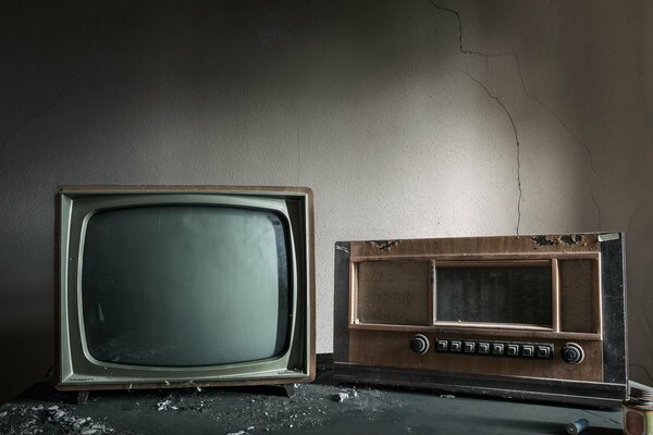 Alte Fernseher und Radio vor dem Hintergrund einer gebrochenen Wand