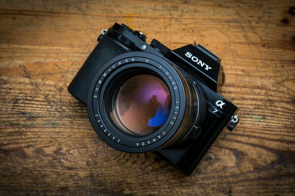 A camera with a large lens on a wooden board