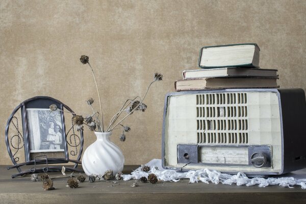 An ancient radio on a table with a white vase