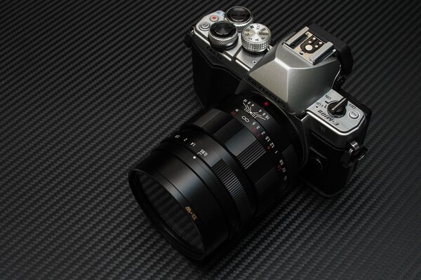 Czarny aparat E-m10 leży na dywaniku w paski