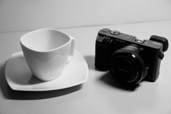 Белая чашка рядом с черным фотоаппартом Sony a600
