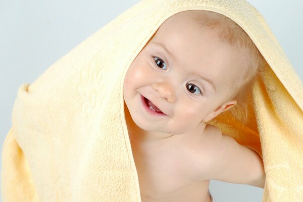 Bambino che fa capolino da sotto un asciugamano di spugna giallo