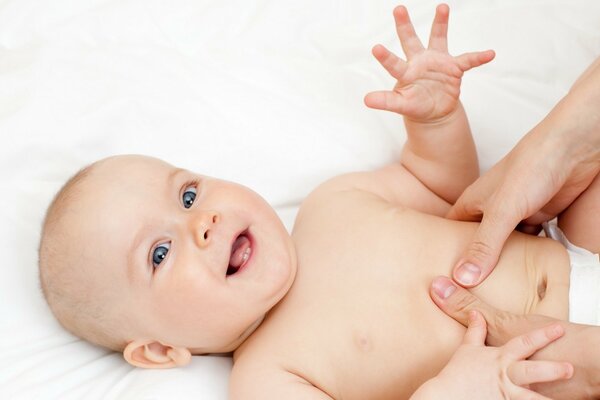 Lindo bebé sonriente y las manos de mamá en su barriga