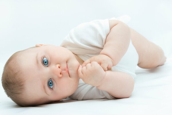 Il bambino giace e guarda con i suoi bellissimi occhi azzurri
