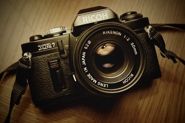 A black Ricoh camera on a wooden background