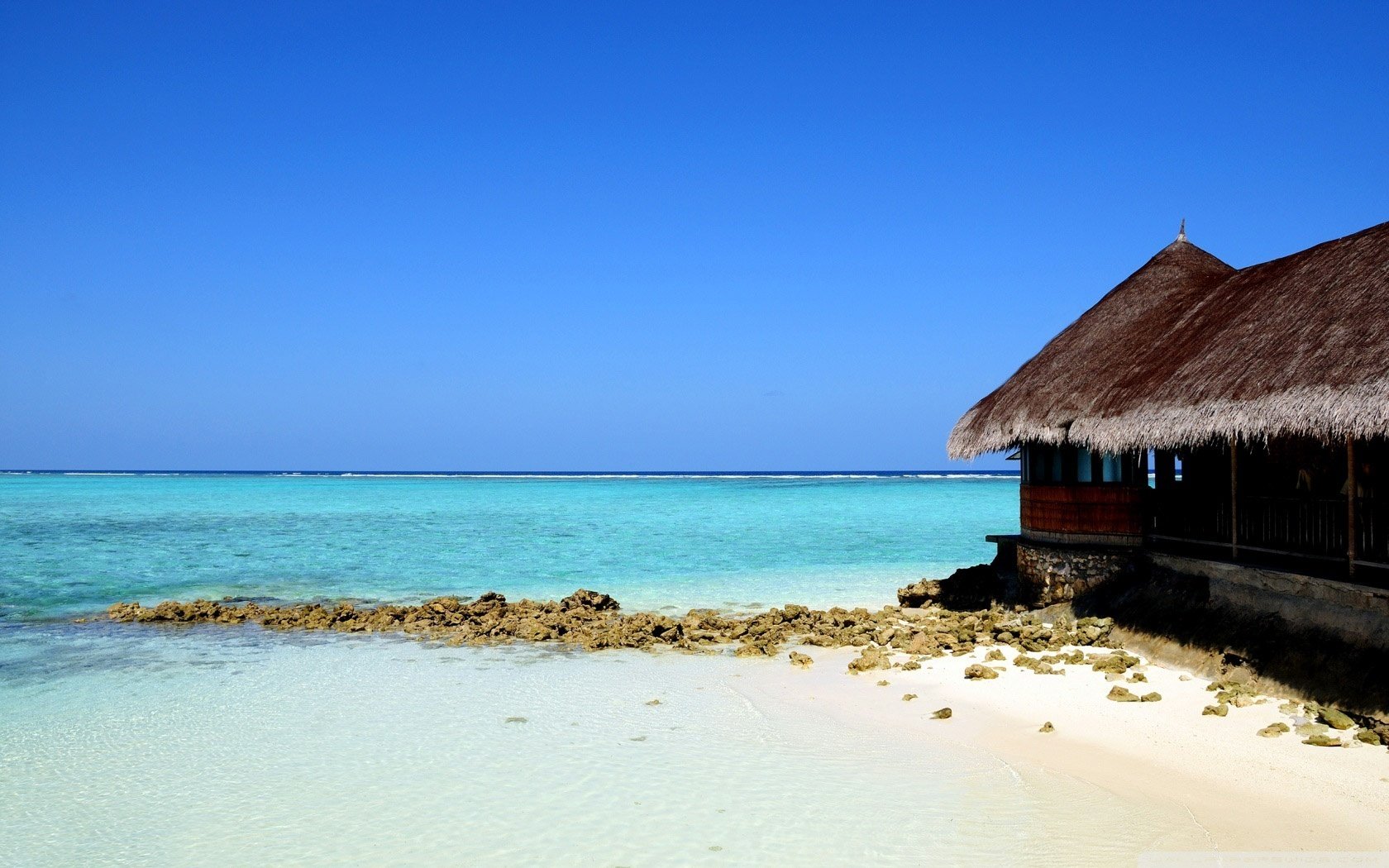 traw house on the seashore sand beach water sky shore horizon recreation nature landscape roofs stones azure clear sky summer heat heat tropics paradise