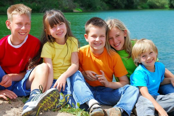 Friendly children by the water on a sunny day. Five smiles