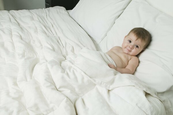 A happy child is lying in bed