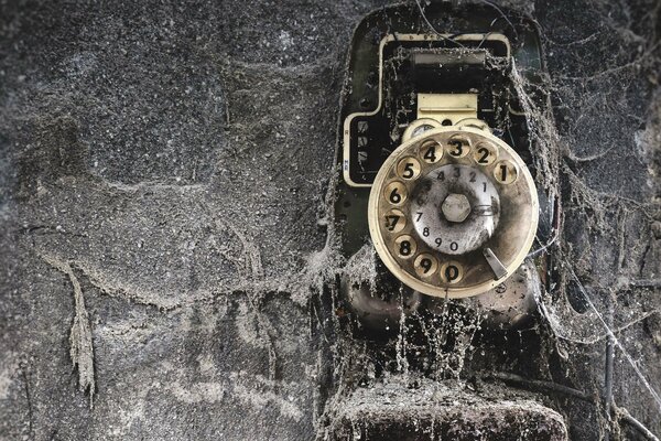 An old wall phone covered in cobwebs and dirt