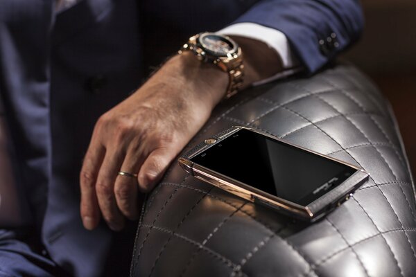 Reloj de oro en la mano y Smartphone