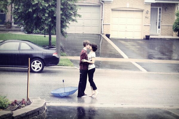 A girl and a guy gently kiss in the rain