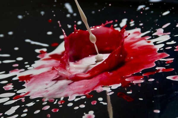 A red and white blob flies in different directions on a black background