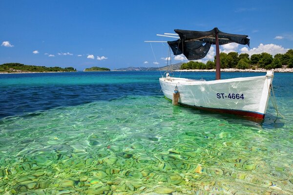 Barco en la orilla del mar con aguas cristalinas