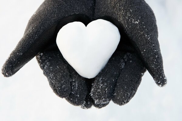 Cuore bianco di neve nei palmi delle mani