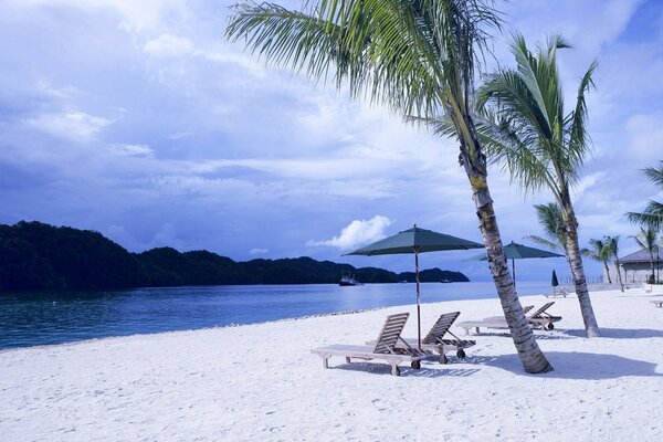 Chaise longue on a white beach in a tropical island