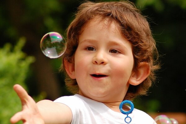 Surprised boy playing with soap bubbles