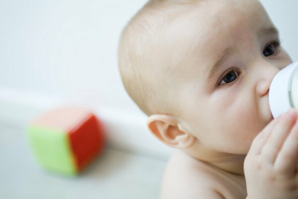 The baby drinks milk from a bottle