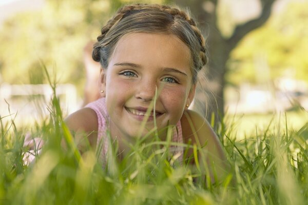 A girl with a charming smile lies in the grass