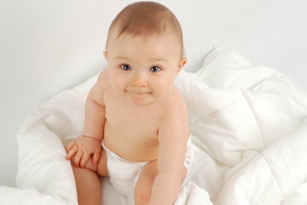 Cute baby on a white blanket in a diaper