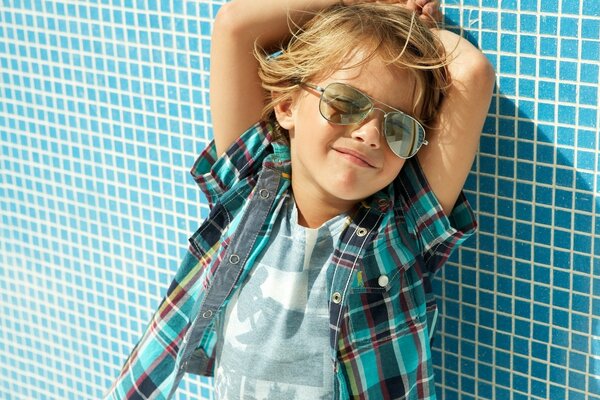 A boy in a plaid shirt against a blue wall