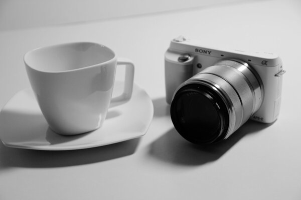 Macchina fotografica e tazza di caffè su piattino