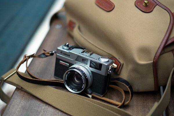 A SLR camera for shooting lies on a beige bag