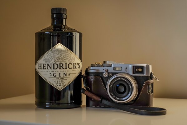 Appareil photo dans un étui sur un fond de bouteille de Gin