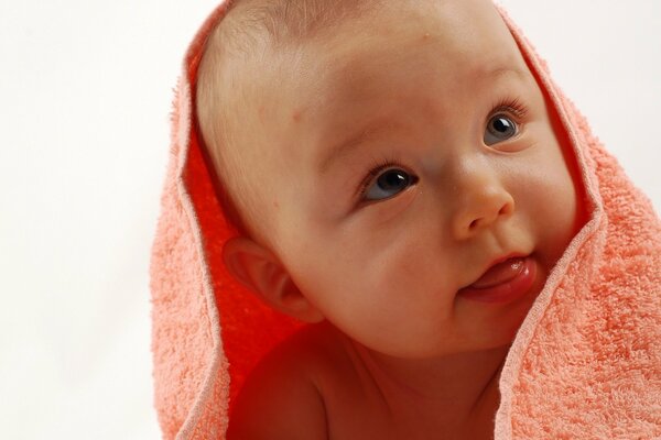 Bébé souriant dans une serviette éponge rose