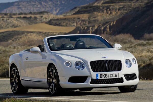 Sur la route au milieu des montagnes se trouve une Bentley blanche