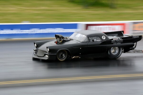 Black muscle car drag racing on the track