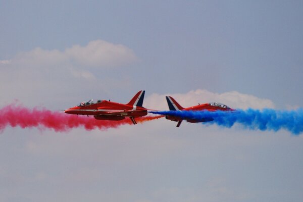 Deux avions volent avec de la fumée rouge et bleue