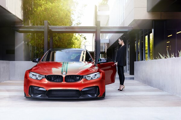 A red bmw car with a girl in black standing next to it