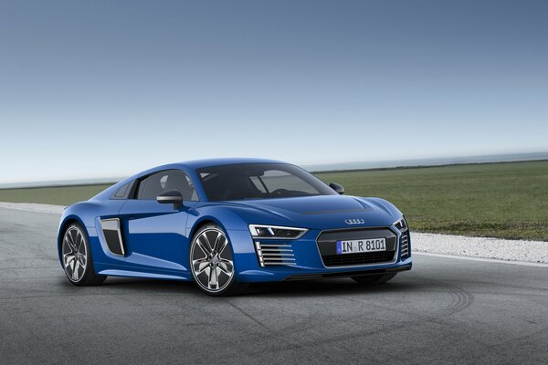 A blue audi is driving on the road