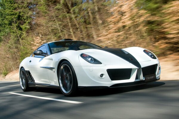 A white Ferrari car is driving at speed on the road