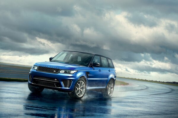 Range rover bleu vif sur fond de nuages gris rassemblés